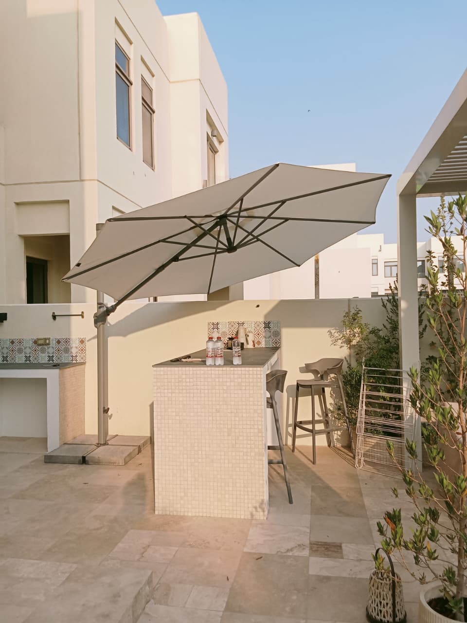 Familyflex cantilever umbrella shading an outdoor bar and stools in Dubai