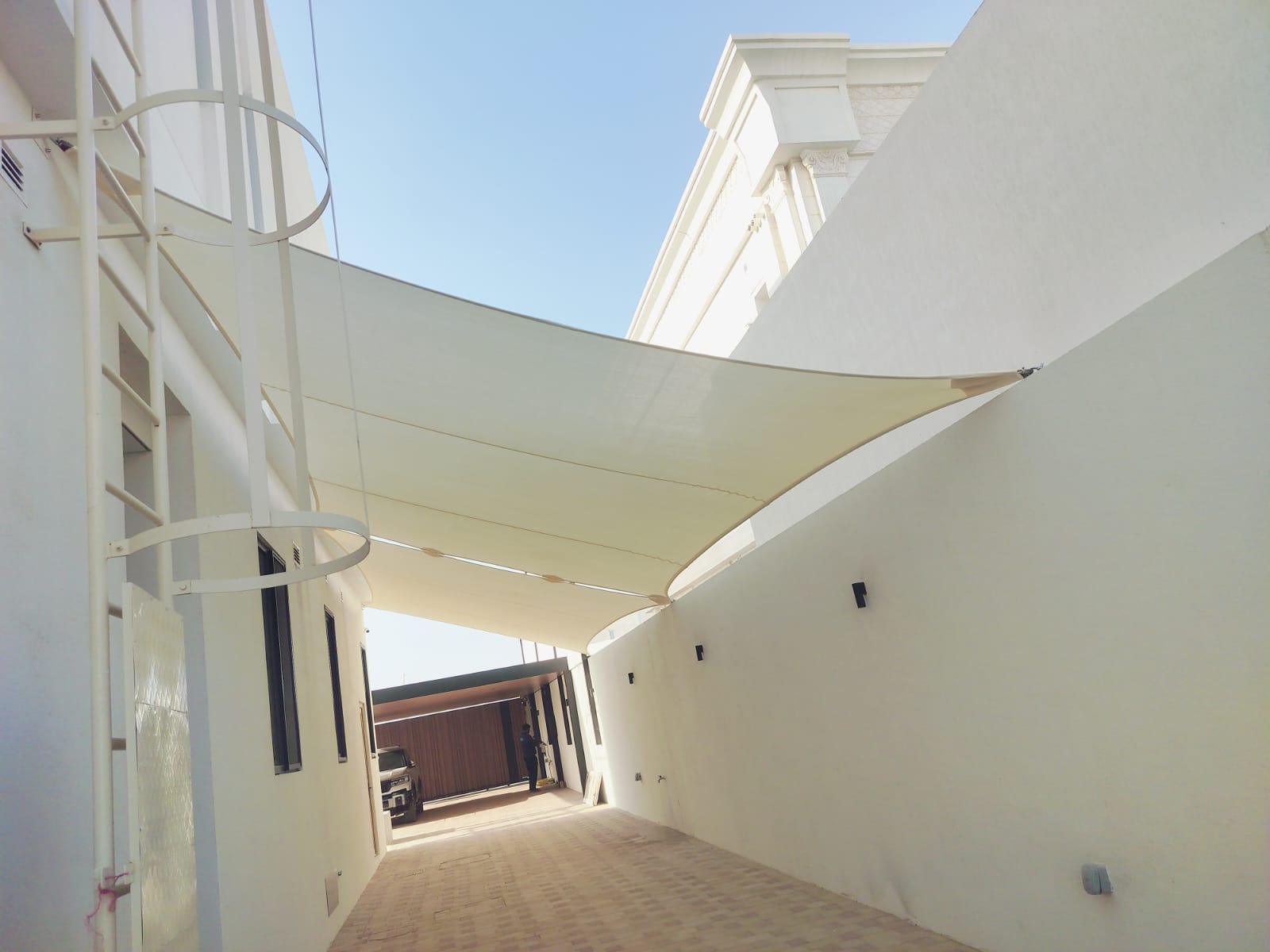 Tensioned shade sail covering a villa side passageway in Dubai with view of parked vehicle