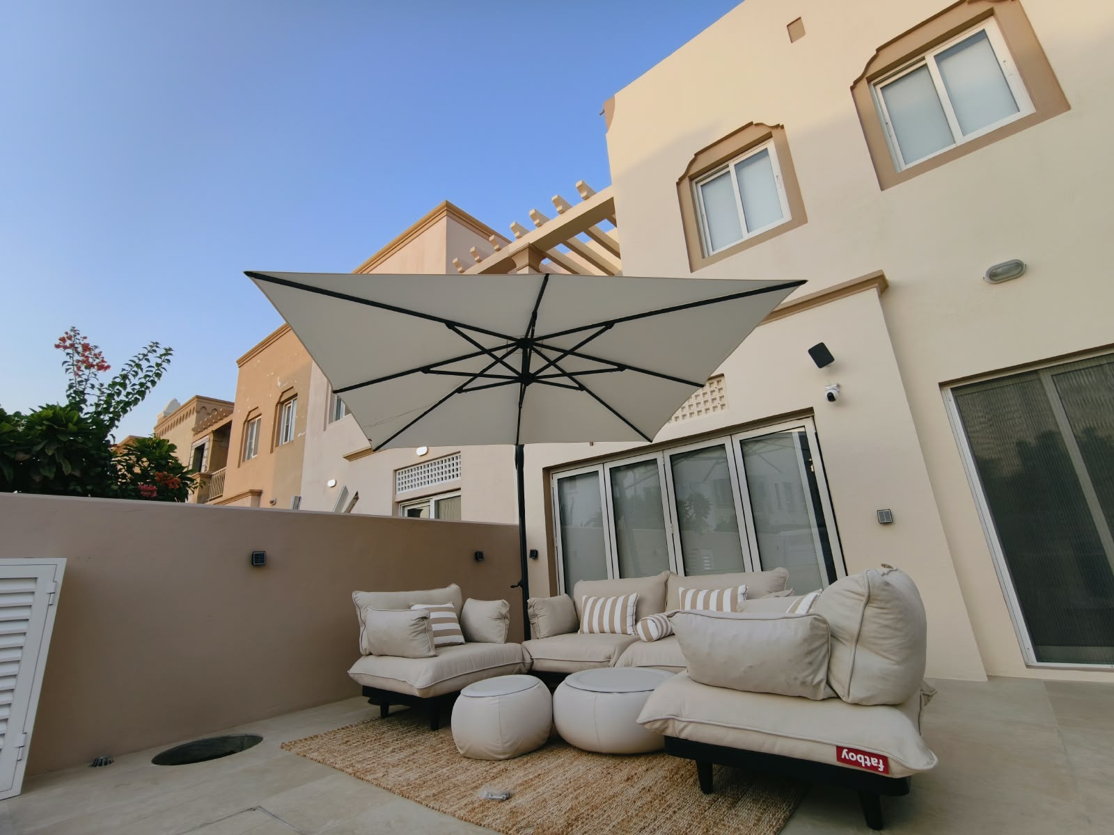 Stone-coloured cantilever umbrella over beige sofa seating in a Springs villa courtyard