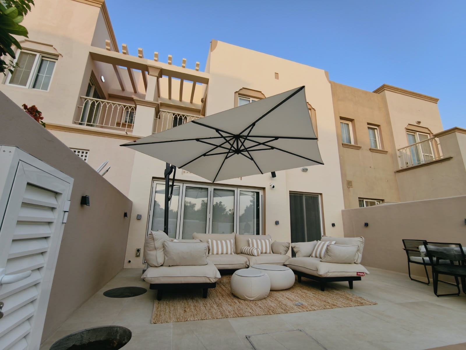 Open cantilever umbrella providing shade over outdoor seating near glass doors in The Springs