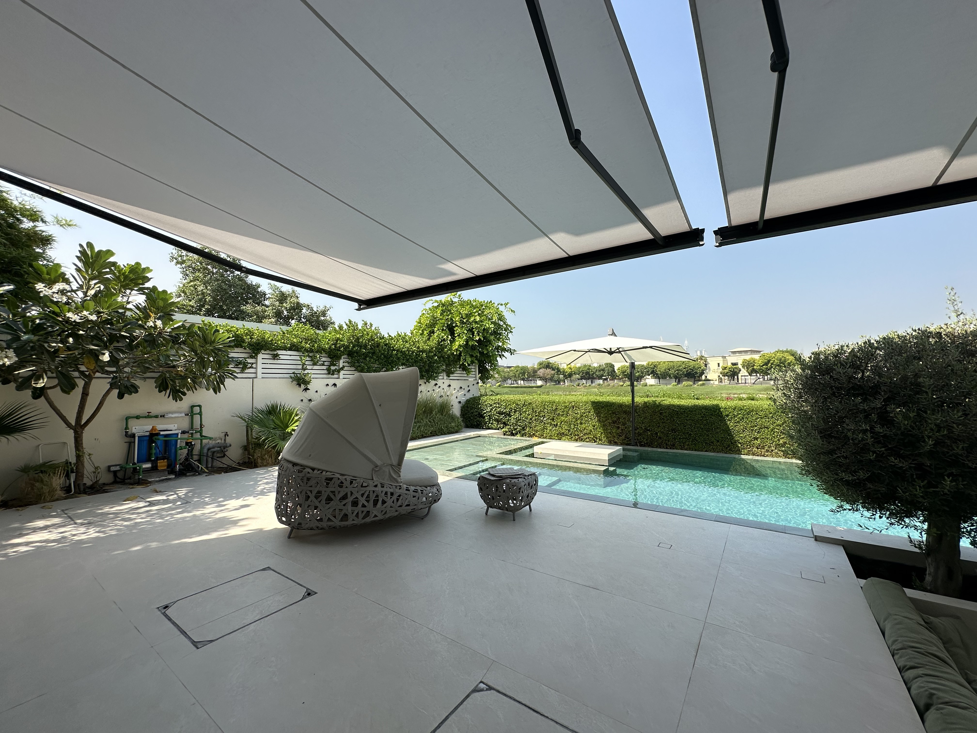 Retractable awning shading a poolside terrace with lounge seating in Meadows, Dubai